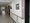 Ein heller, langer Flur, vermutlich in einem Krankenhaus oder Pflegeheim. An der rechten weißen Wand verläuft ein Holzhandlauf. An der Wand hängen Bilder und sind mehrere dunkle Türen zu sehen. Am Ende des Ganges führt eine Glastür ins Freie.